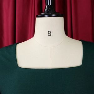 Primer plano del elegante escote cuadrado de un vestido de punto verde oscuro en un maniquí