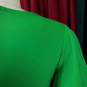 Detail of shoulder seam and ruffle sleeve texture on a bright green bandage dress