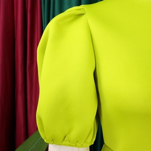 Détail de la manche bouffante vert fluo avec poignets élastiques et tissu structuré chic