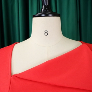 Detail view of red asymmetrical neckline and textured fabric on tailor mannequin