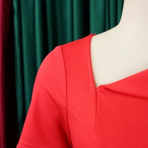 Detailed view of asymmetric neckline and red knitted fabric texture with stitching