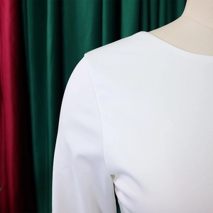 Gros plan détaillé d'une robe blanche à col rond montrant le tissu lisse et la couture