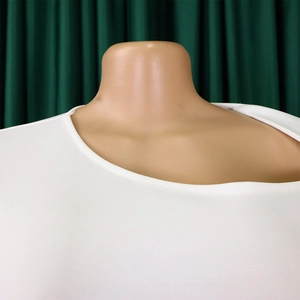 Detail of white textured fabric with asymmetrical neckline on commuter dress