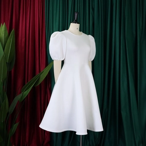 Détail d'une robe blanche élégante à manches bouffantes, col rond et coupe évasée