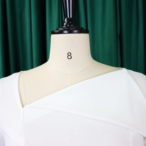 Detail of the white asymmetrical off-shoulder neckline and premium textured fabric