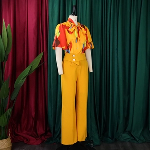 Detail der bedruckten Schluppenbluse und gelben Weitbeinhose mit Knopfverzierung