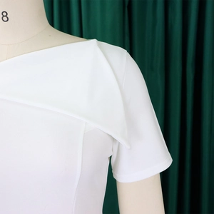 Detail of white asymmetric dress showing the modern wide geometric lapel and shoulder cut