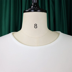 Gros plan du haut blanc à col rond et finitions de l'encolure sur un mannequin de couture