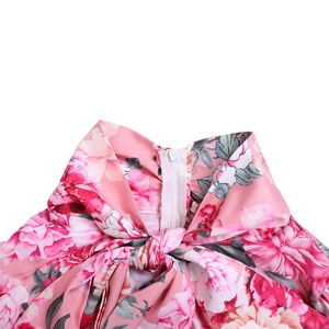 Dettaglio dell'abito a fiori rosa con cerniera sullo scollo e fiocco decorativo sul petto