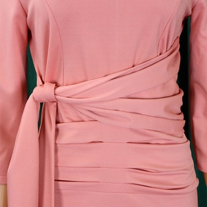 Detail of waist cross-tie design and ruched fabric on pink long-sleeve dress