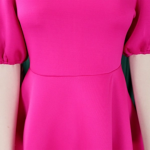 Dettaglio del vestito rosa acceso con taglio sciancrato in vita e maniche a palloncino