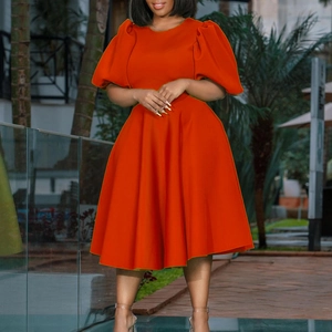 Detail of vibrant orange A-line dress featuring dramatic puff sleeves and a cinched waistline