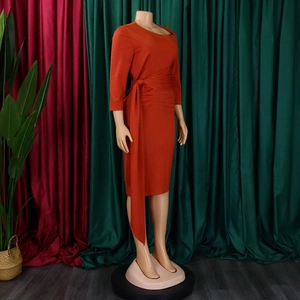 Detail view of the terracotta office dress featuring elegant waist pleats and side tie