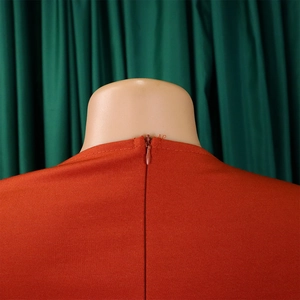 Close-up of a burnt orange dress featuring a hidden zipper and fine fabric texture