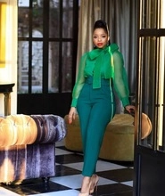 Close-up of green chiffon shirt with oversized bow tie and high-waist trousers