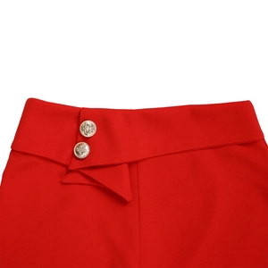 Detail der roten Hose mit hoher Taille, goldenen Reliefknöpfen und asymmetrischer Taille