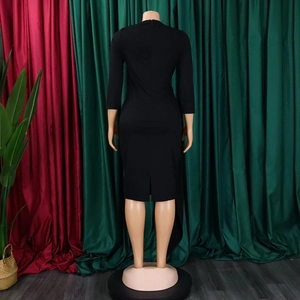 Detail view of back split hem and invisible zipper on black fitted midi dress