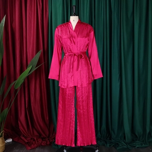 Detaillierte Textur aus rosarotem, plissiertem Satin-Oberteil und weiter Hose als Set