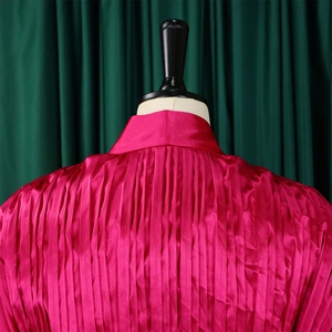 Detail der fuchsiafarbenen Plissee-Bluse mit Satin-Textur und vertikalen Falten für Damen