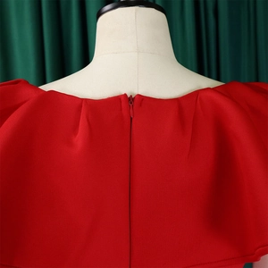 Détail d'une robe de soirée rouge avec col à volants et fermeture éclair invisible au dos