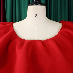 Détail d'une robe de soirée rouge épaules dénudées avec encolure à volants et manches bouffantes