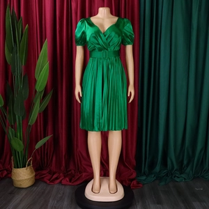 Detail of green satin pleated dress featuring a deep V-neckline and matching waist belt