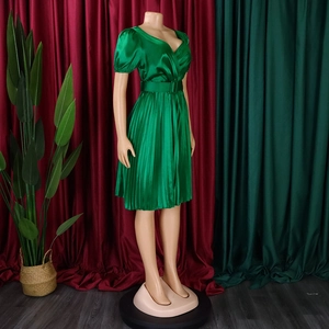 Detail of green satin pleated dress with deep V-neck and matching waist belt