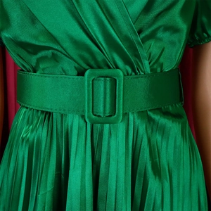 Close-up of emerald green satin dress featuring pleated waist and matching square buckle belt