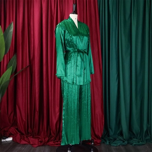 Detail eines smaragdgrünen Satin-Lounge-Sets mit V-Ausschnitt, Gürtel und Faltenhose