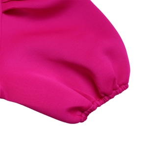 Dettaglio del polsino elastico su un abito fucsia a trapezio con trama di tessuto liscia