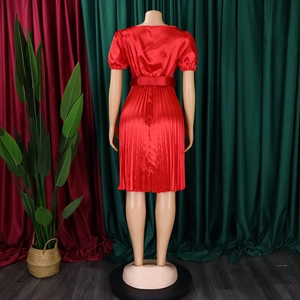 Detail of red satin dress featuring a pleated skirt and matching wide waist belt
