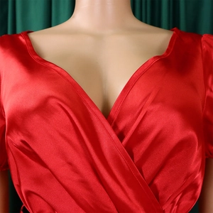 Detail of red satin wrap dress with deep V-neckline and elegant pleated sleeve texture