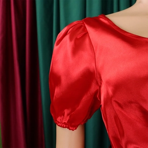 Detail of red satin dress featuring elegant puff sleeves and smooth silk texture