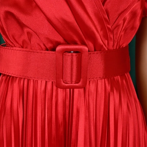 Detail of red satin dress featuring a square buckle belt and fine pleated skirt texture
