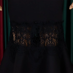 Detailed close-up of intricate lace waist patchwork on a black off-shoulder fishtail dress