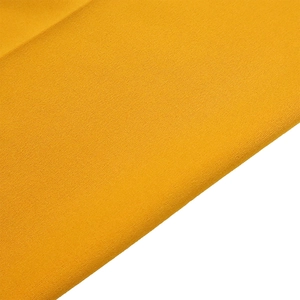 Macro shot of ginger yellow chiffon fabric with a textured grainy weave for women pants
