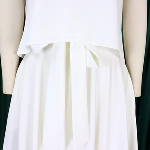 Detail of the white chiffon outfit featuring a stylish wide waist bow and layered design
