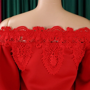 Detailed close-up of red floral lace embroidery on an elegant off-the-shoulder gown