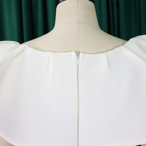 Détail de la robe blanche montrant la fermeture éclair invisible et l'encolure plissée