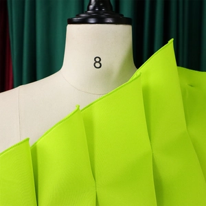 Detail of neon green pleated fabric showing vertical texture on a display mannequin