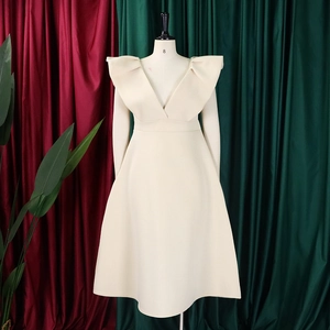 Detalle de los espectaculares hombros con volantes y escote en V profundo del vestido beige
