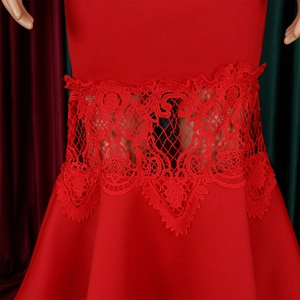 Detailed view of intricate floral lace embroidery on the waist of a red evening gown