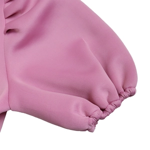 Dettaglio ravvicinato delle maniche a sbuffo rosa con polsini elastici e trama fine