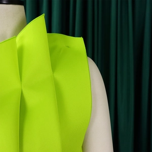 Detail of neon green sculptural pleats and fine overlock stitching on formal dress