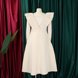 Detalle del diseño de espalda con escote en V profundo y volantes en el vestido crema