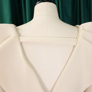 Detalle de vestido crema con espalda descubierta, escote en V y mangas abullonadas