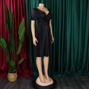 Detail of black V-neck pleated dress with satin finish and matching waist belt