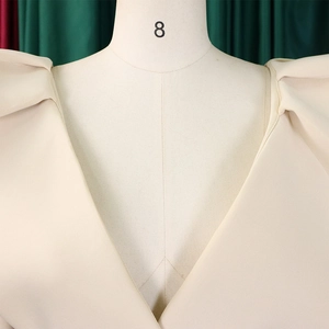 Detalle del escote en V y las mangas abullonadas plisadas en el vestido de fiesta crema