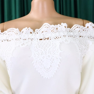 Detail view of white off-shoulder neckline featuring intricate crochet lace and mesh splicing