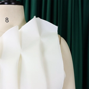 Macro detail of white pleated shoulder design on a formal evening gown for women